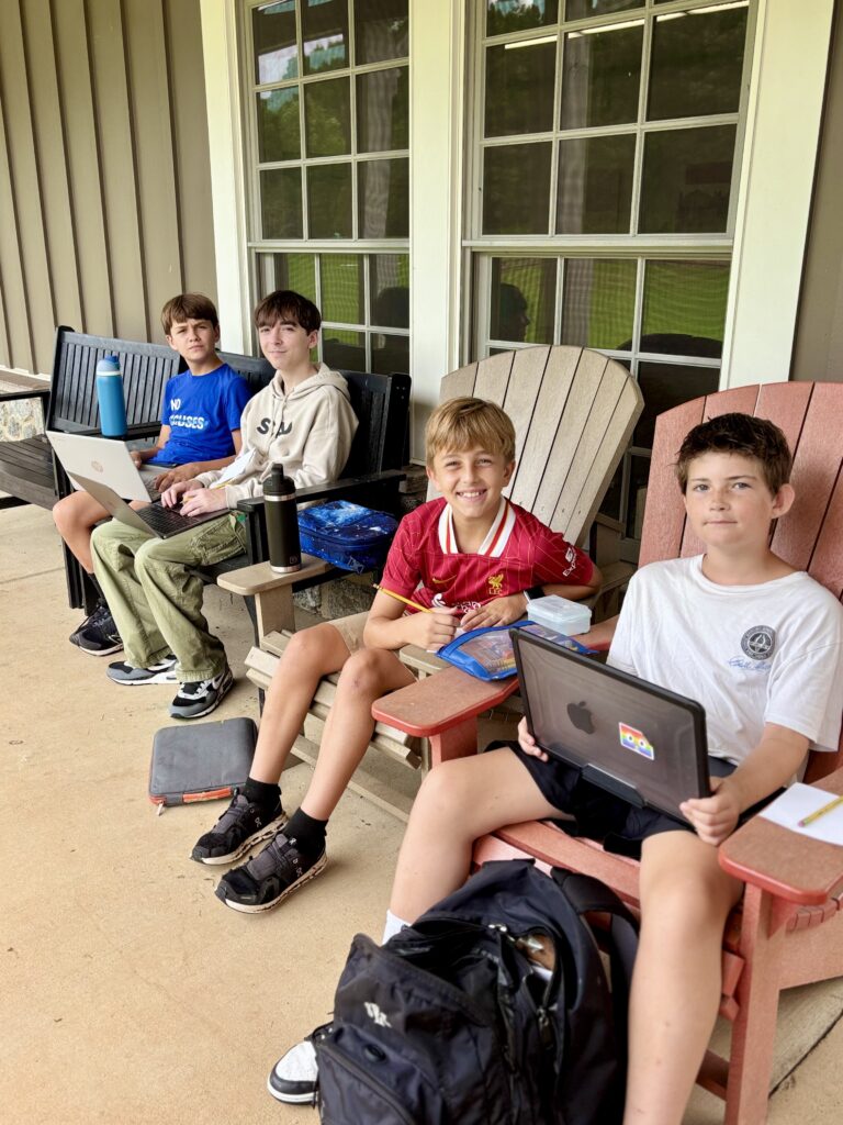 Students using laptops outdoors at Woodlawn School.