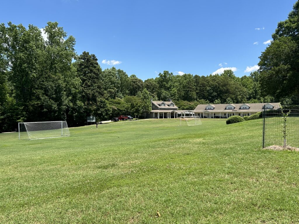 Open field and tree line on Woodlawn School's 61-acre Mooresville campus.