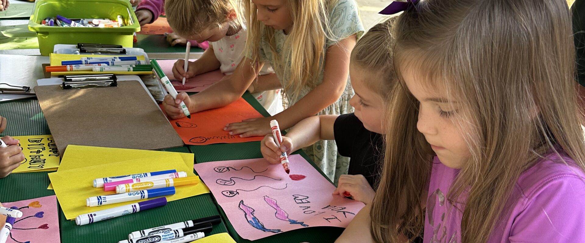 Children creating colorful posters outdoors at Woodlawn School.