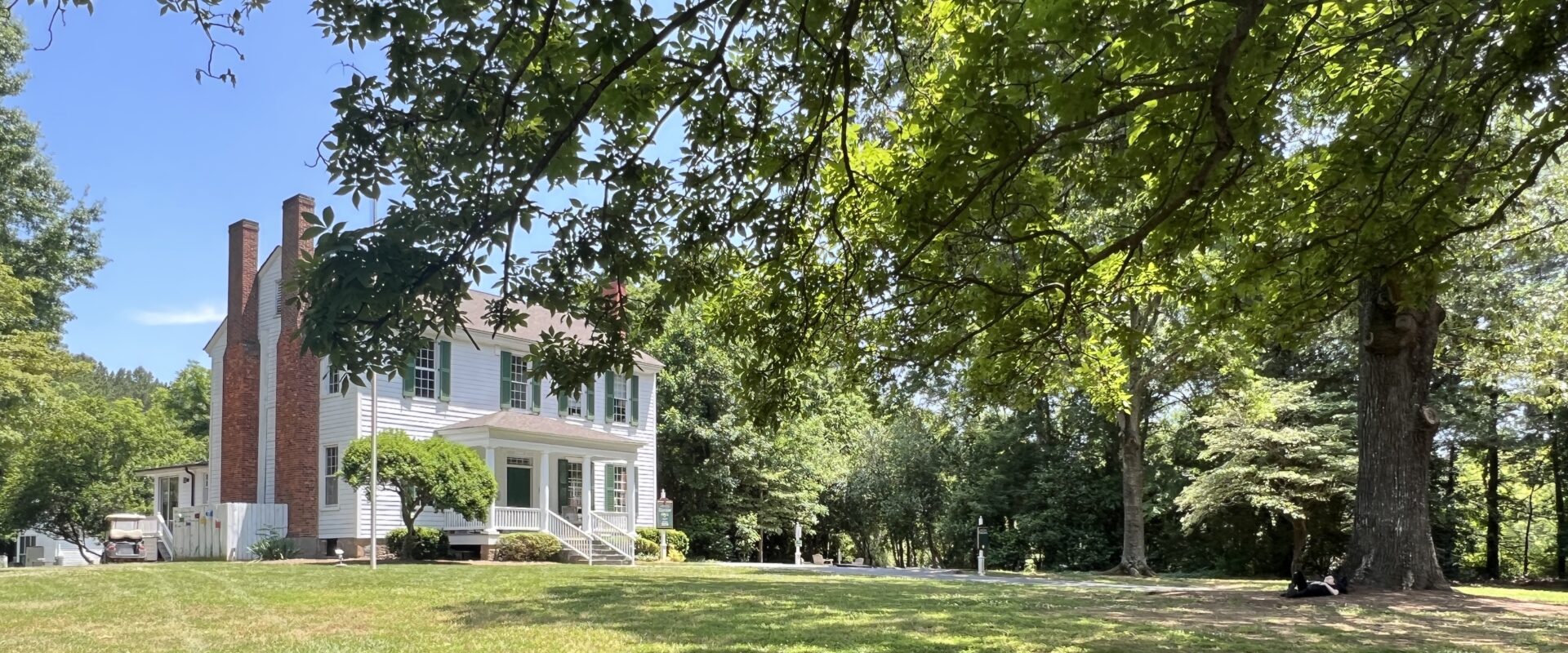 The historic house at the heart of Woodlawn School's campus, framed by oak trees.