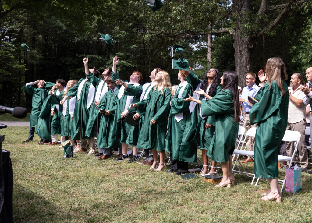 Woodlawn School's Class of 2026 throwing their caps at graduation.